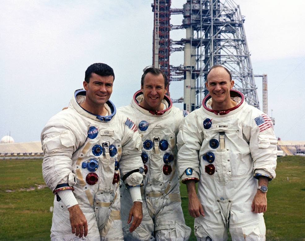 A tripulação original da Apollo 13 (a partir da esquerda): Haise, Lovell e Mattingly posam em frente ao foguete Saturno V.