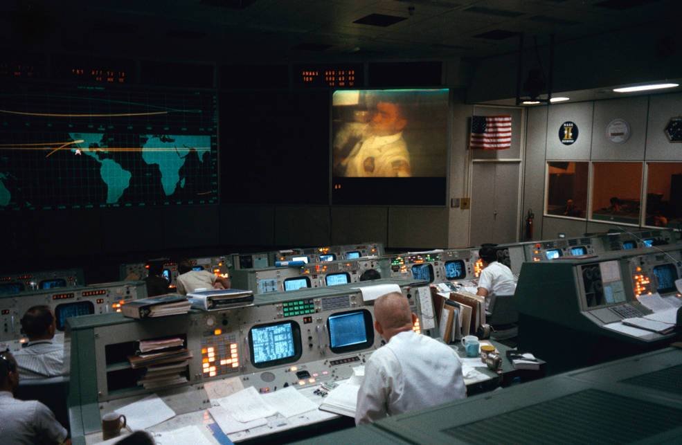 O diretor de vôo Eugene Kranz (em primeiro plano) assiste à equipe da Apollo 13 em uma transmissão de TV apenas alguns minutos antes da explosão.