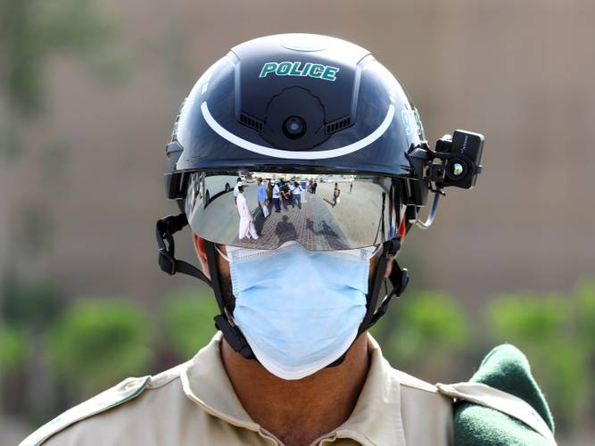Um policial usa o capacete inteligente para verificar a temperatura de pessoas na rua em 23 de abril de 2020, Dubai