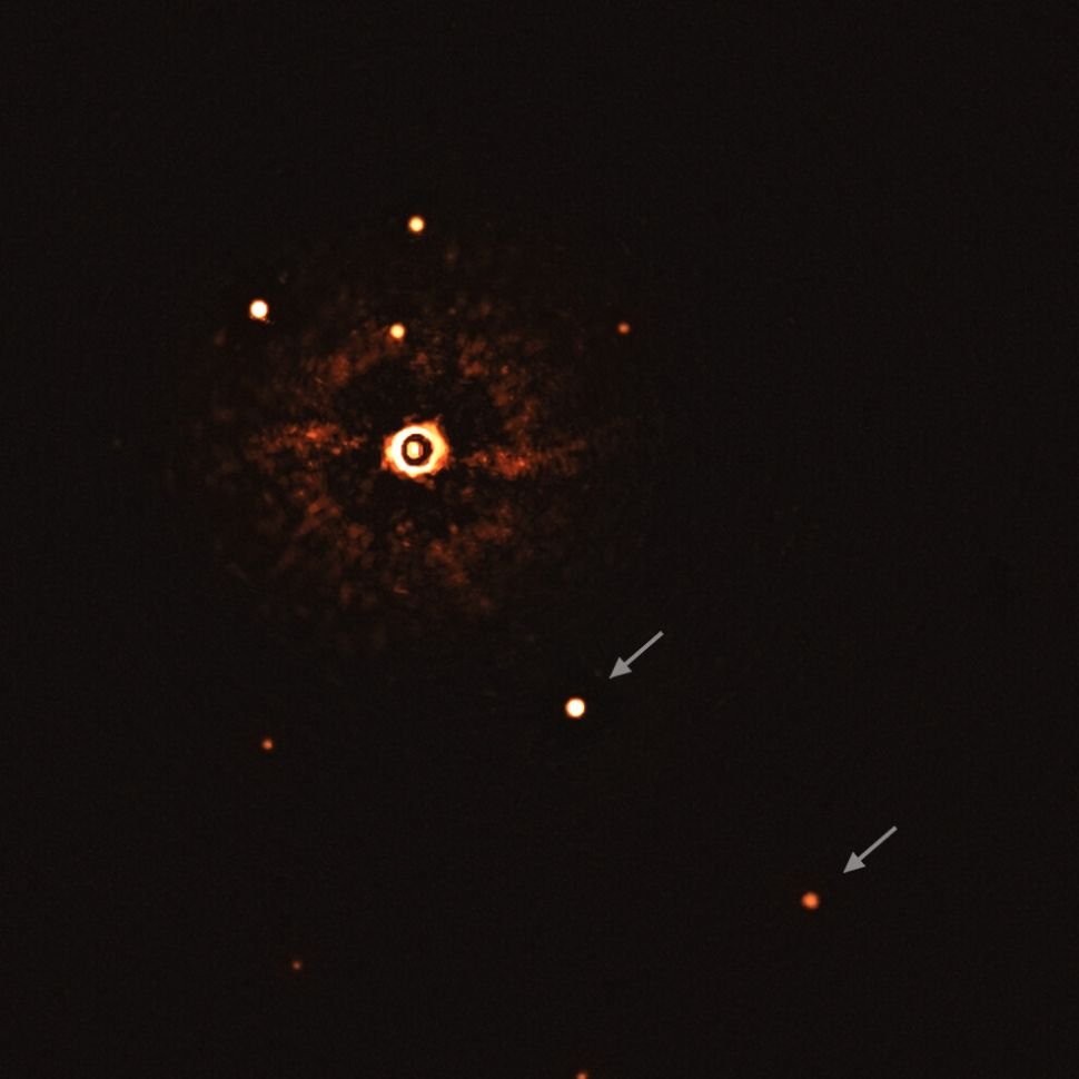 O brilho mais forte é a estrela, com os dois planetas indicados pelas setas. (Fonte: ESO/Bohn et al./Divulgação)