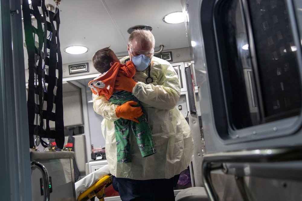 Um paramédico carrega um bebê de dez meses com suspeita de covid-19 em Stamford, Califórnia.