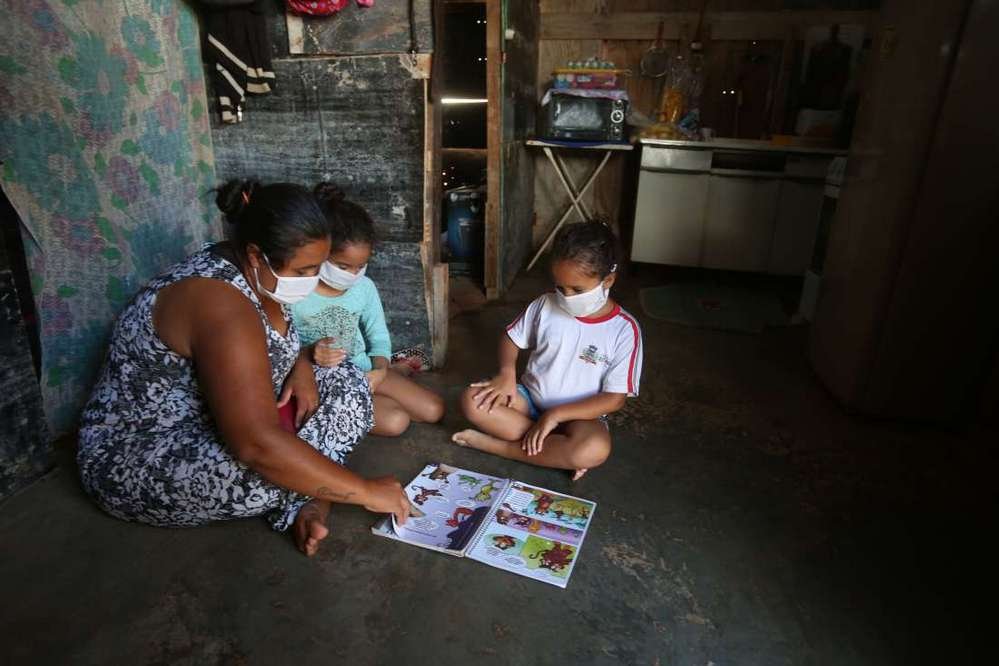 No chão de casa, em uma favela de São José do Rio Preto (SP), uma mãe tenta ensinar os filhos sem um computador ou internet. Segundo o IBGE, 46 milhões de pessoas no Brasil não têm acesso às redes.