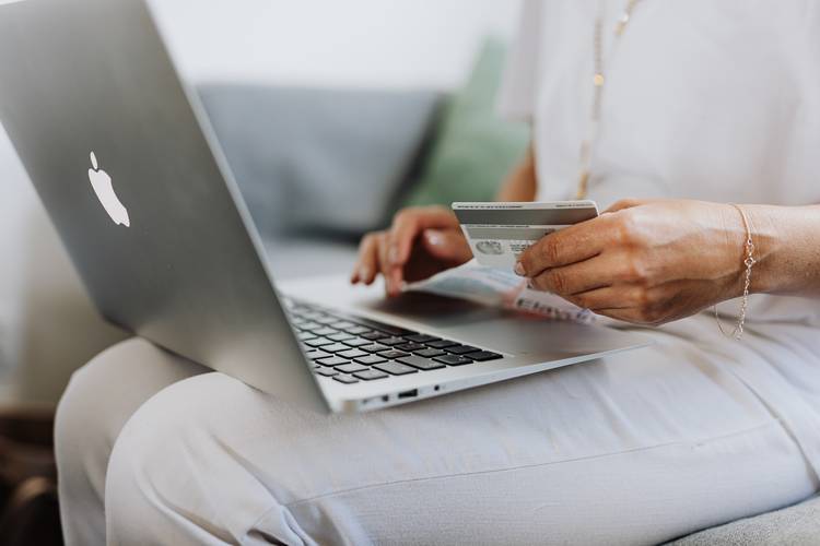 Mulher fazendo compra online em um notebook e pagando com cartão de crédito.