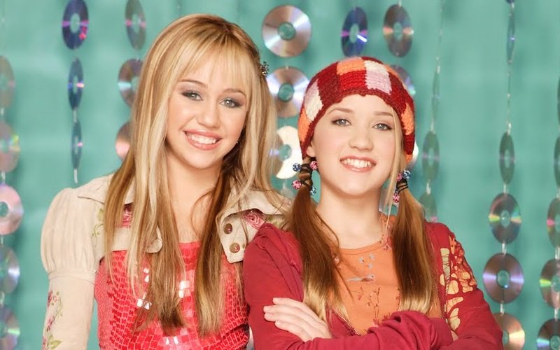 Miley Cyrus e Emily Osment lado a lado em Hannah Montana. (Fonte: Disney/Reprodução)