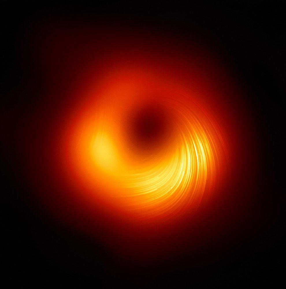 A visão polarizada do buraco negro em M87: as linhas marcam a orientação da polarização, relacionada ao campo magnético ao redor da sombra do buraco negro.