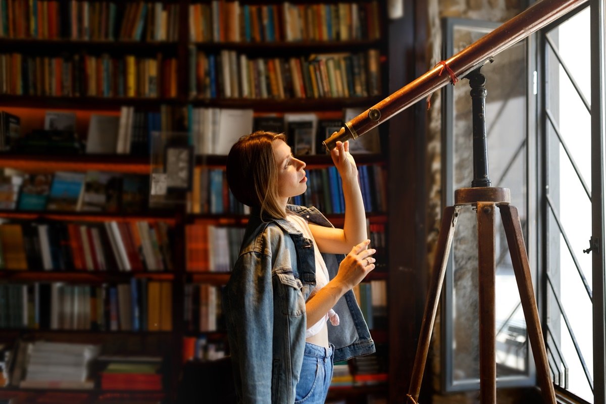 Mulher usa telescópio dentro de uma biblioteca