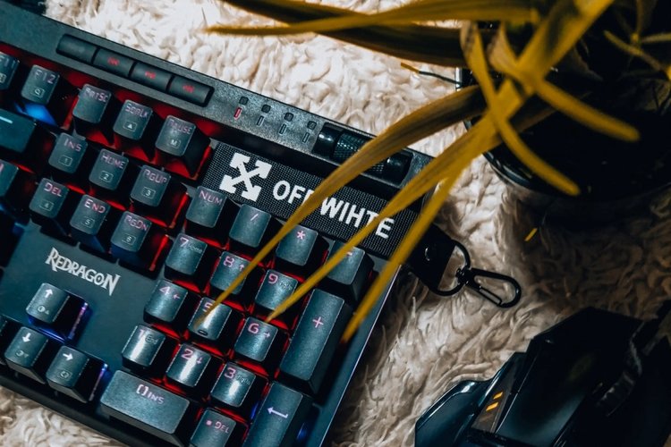 Teclado Redragon com teclas multimídia e botão giratório para controle de volume.