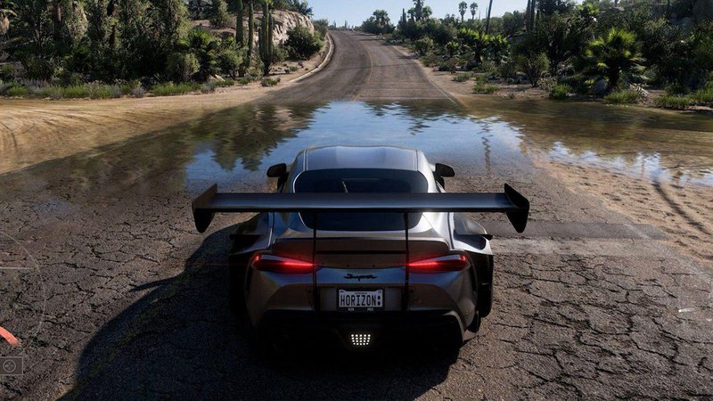 Descrição da imagem: um carro correndo em uma floresta, quase passando por dentro de um rio.