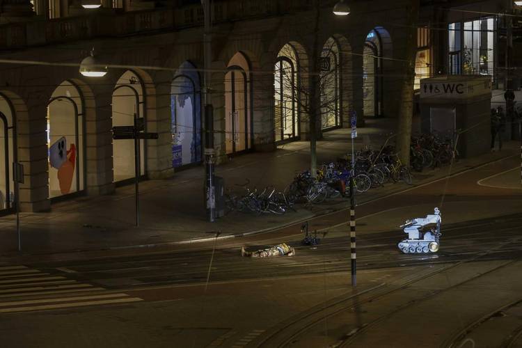 Atirador no chão com robô policial verificando a existência de bombas