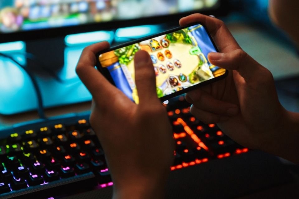 Rapaz sério jogando jogo online no celular, seus dois pais