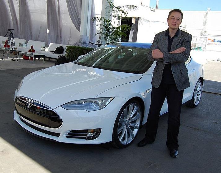 Musk e um Tesla em uma das fábricas da empresa.