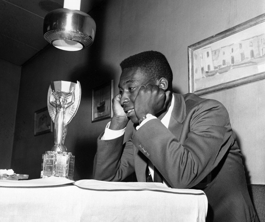 Pelé olhando para a Taça Jules Rimet depois de conquistá-la na Copa do Mundo da Suécia, em 1958