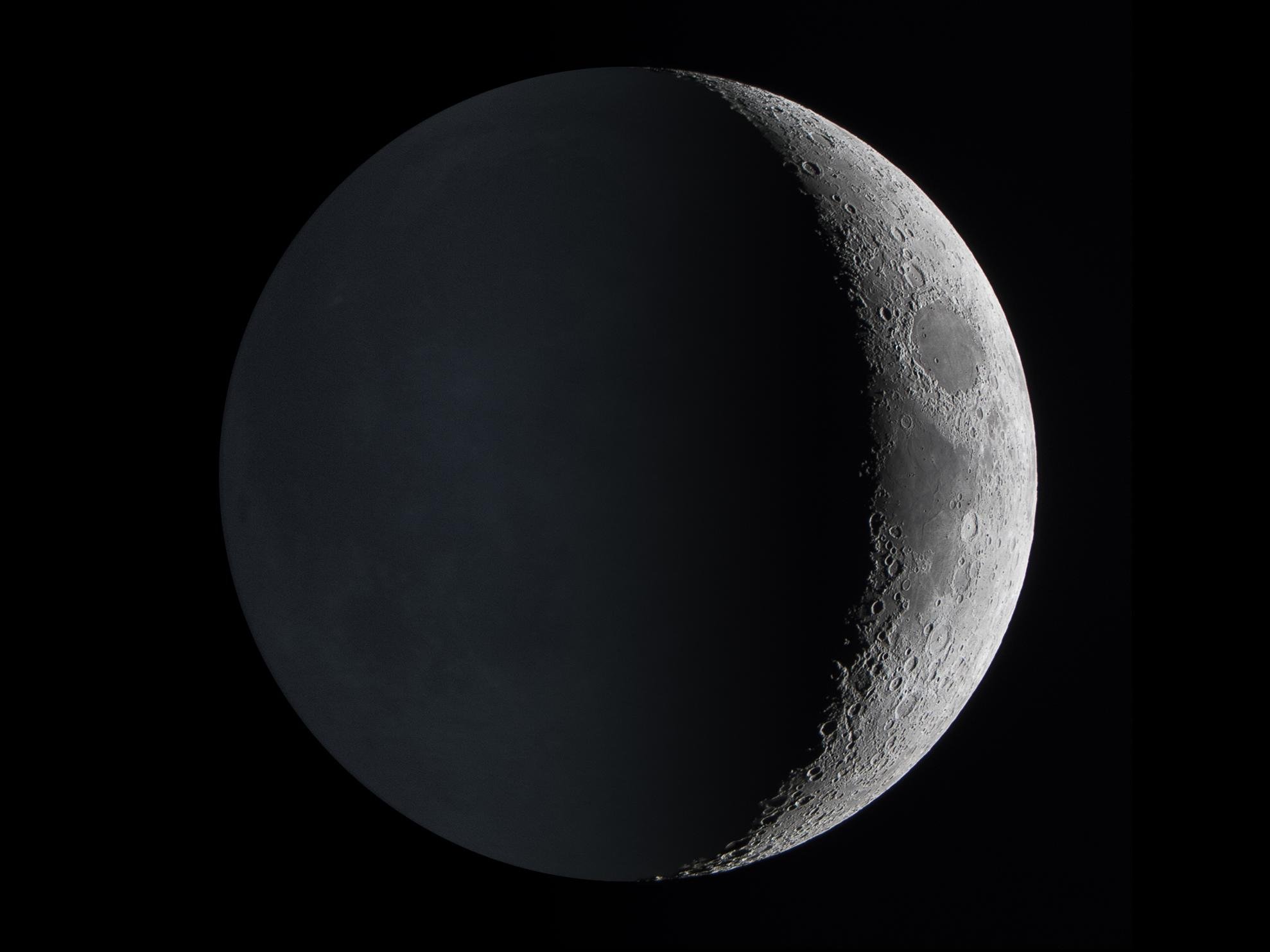 O brilho da Terra é visto refletindo no lado mais obscurecido da superfície lunar.