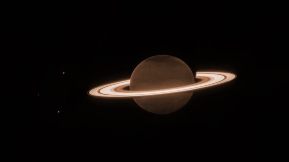 A imagem apresenta Saturno e três de suas Luas, conhecidas como Dione, Encélado e Tétis.