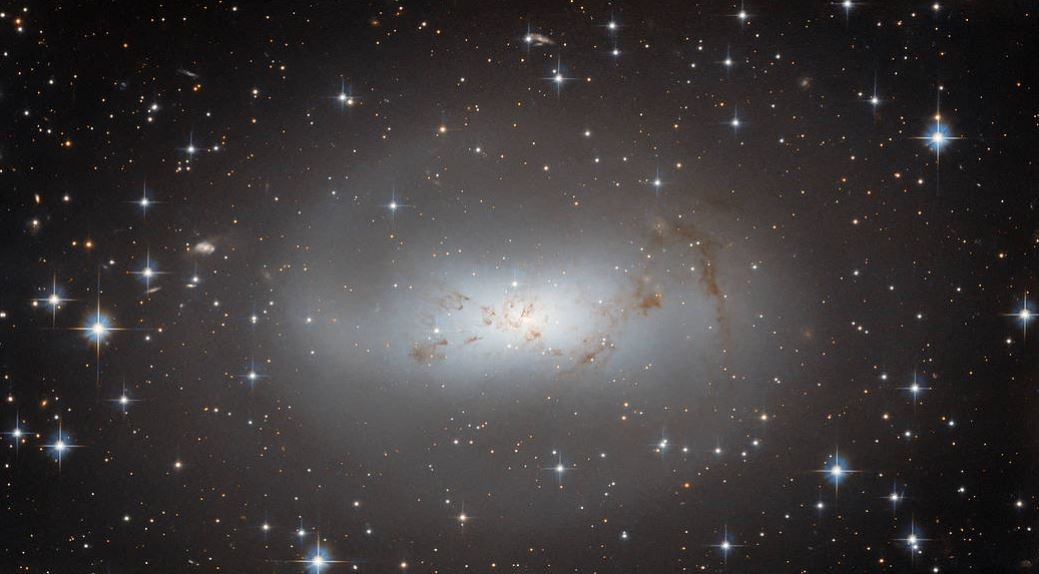 A galáxia ESO 174-1 é representada pela nuvem branca no centro da imagem.