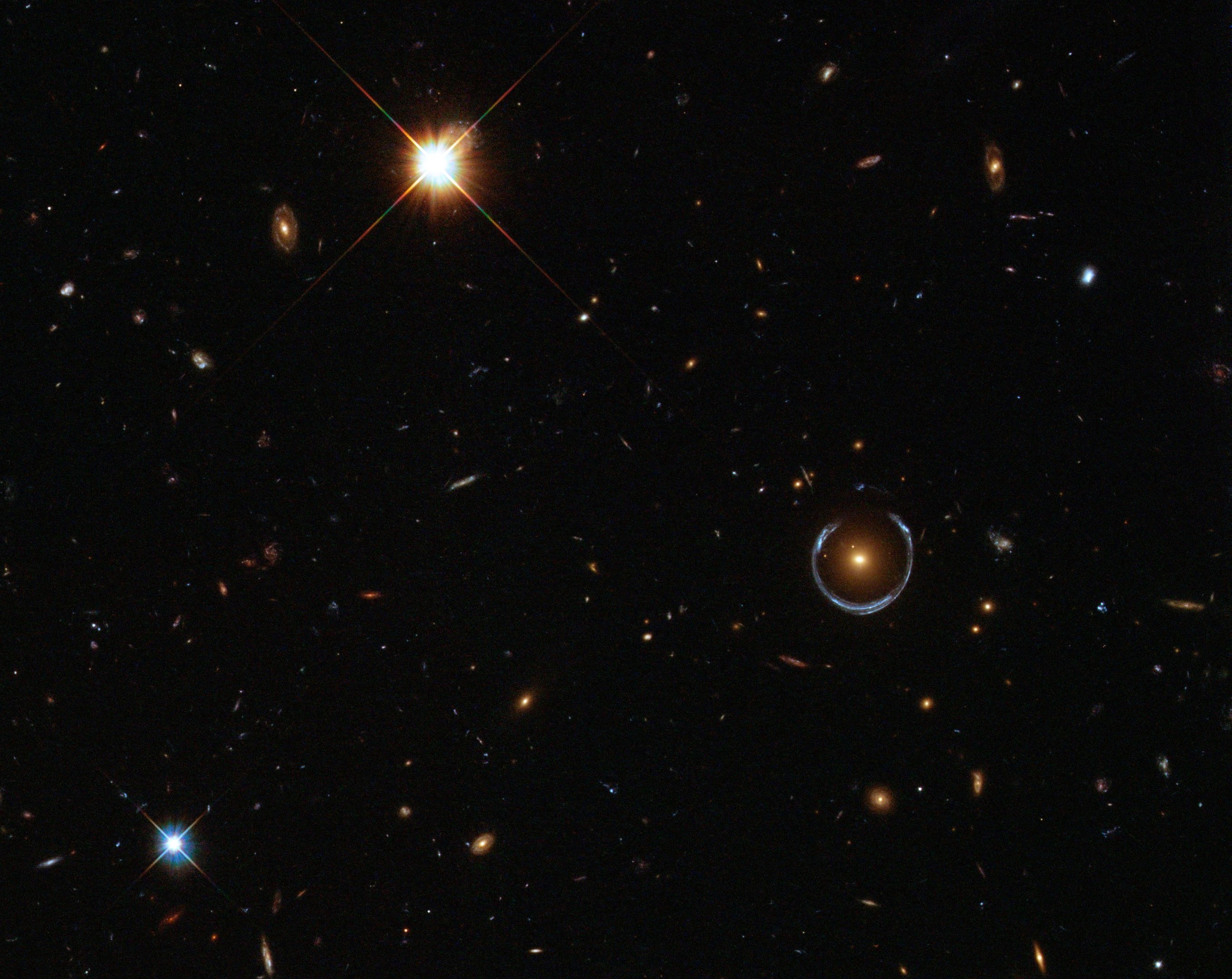 Galáxia distorcendo a luz de uma galáxia mais distante (à direita) criando um Anel de Einstein.