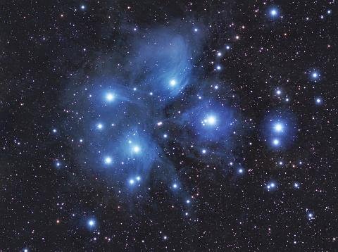 O aglomerado de estrelas das Plêiades conecta galáxias por filamentos de gás e poeira.