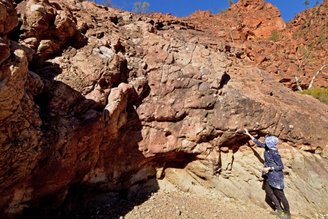 Autora Adriana Dutkiewicz, apontando para um leito de depósitos glaciais na cordilheira de Flinders.