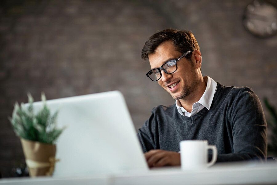 Homem sorrindo enquanto trabalha usando o ChatGPT para ajudar com fórmulas do Excel.