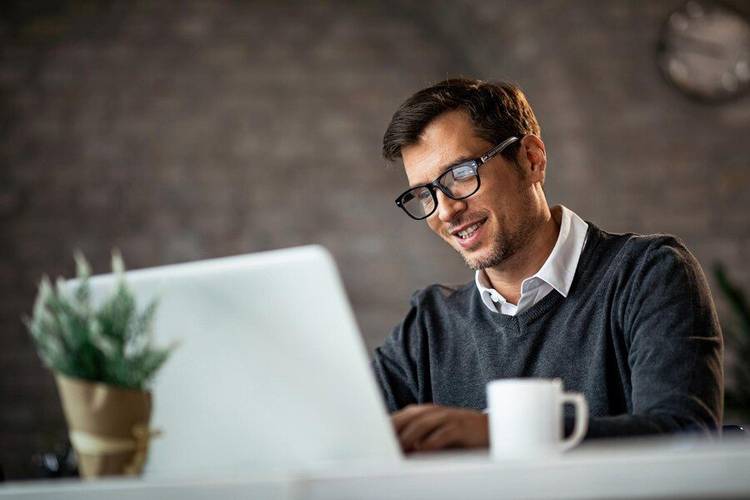 Homem sorrindo enquanto trabalha usando o ChatGPT para ajudar com fórmulas do Excel.