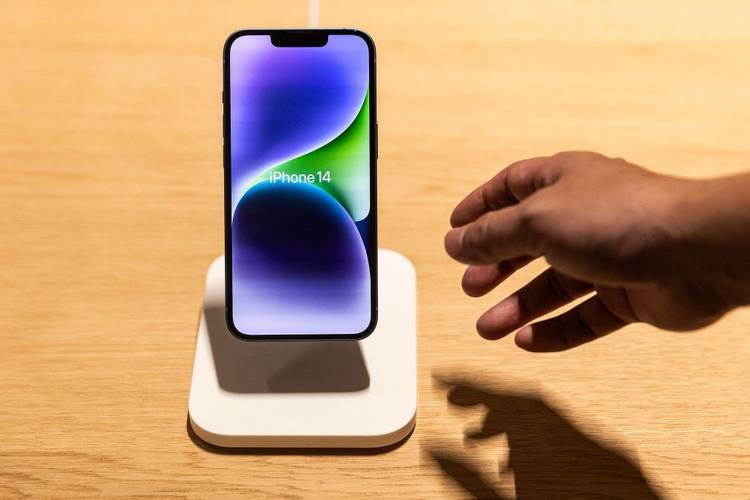 iPhone 14 com uma mão indo pegá-lo.