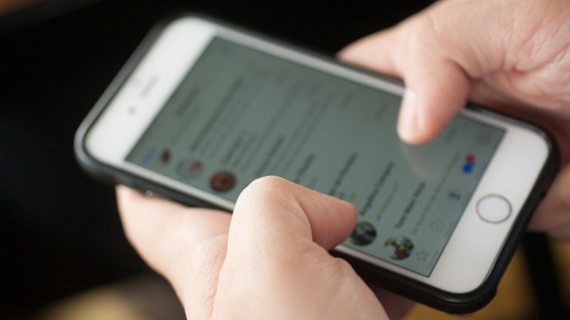 Foto de uma pessoa segurando um celular e usando o WhatsApp
