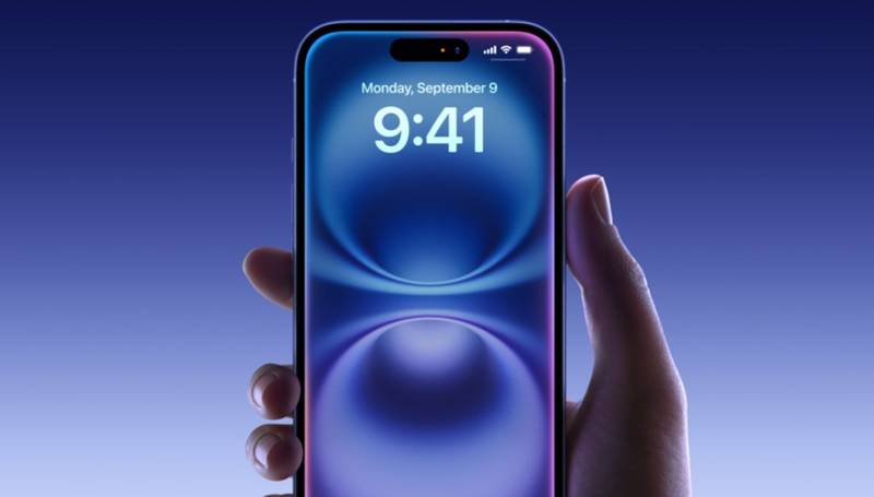 Uma mão segurando um iPhone 16 na cor azul, com a tela ligada na página de debloqueio.