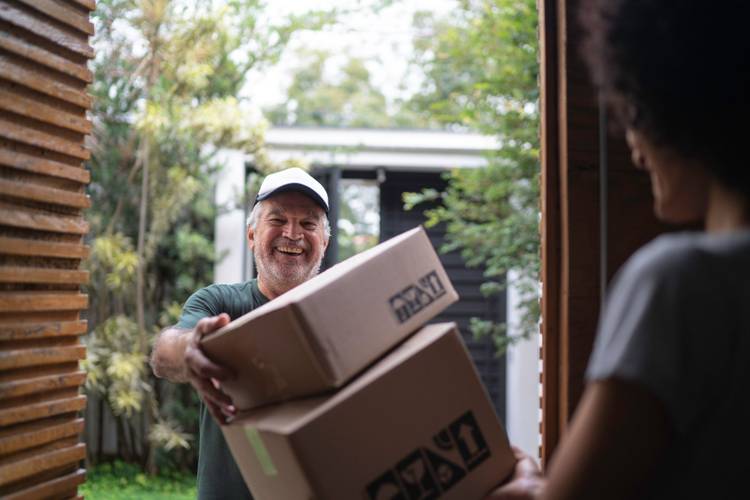 Foto de um homem entregando caixas de papelão a uma mulher