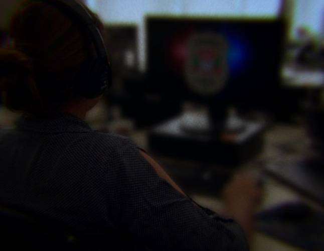 uma pessoa vista de costas em uma foto borrada, acessando um computador com a logo da Polícia Civil.