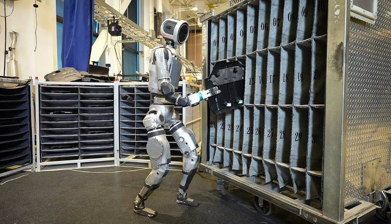 O robô Atlas da Boston Dynamics colocando uma peça de metal em uma gaveta.
