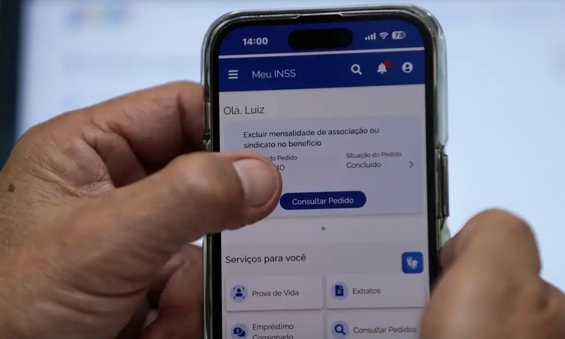 duas mãos segurando um celular com o Meu INSS aberto