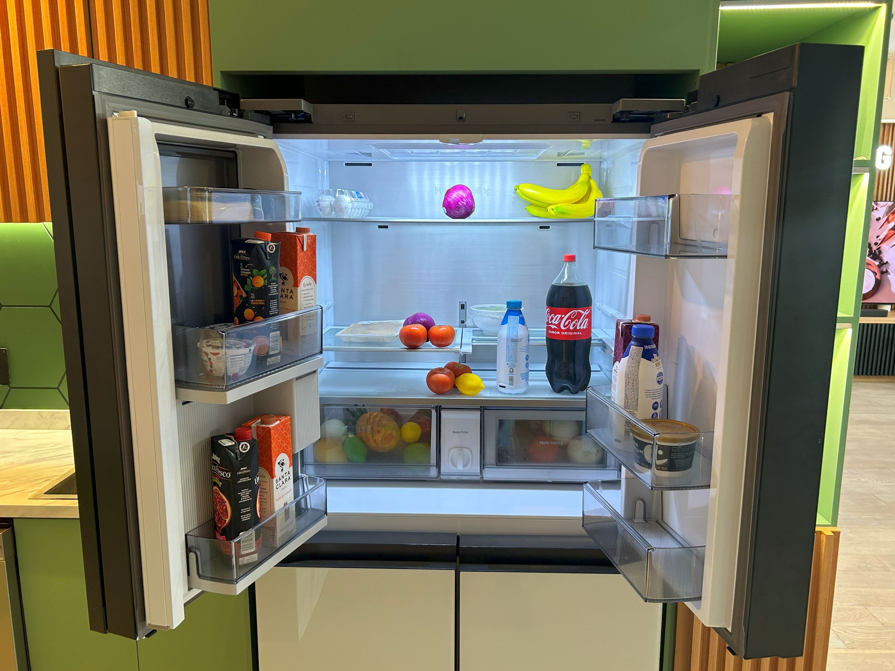 Geladeira Samsung Bespoke AI RM90 com as portas superiores abertas mostrando interior com seleção variada de frutas, vegetais, bebidas e alimentos