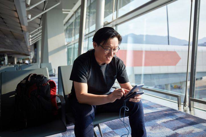 homem-mexendo-no-celular-sentado-no-aeroporto
