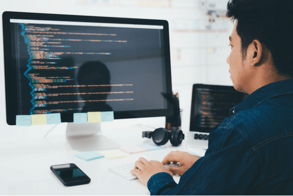 homem-programador-trabalhando-em-código-na-tela-computador-dupla-tela-linguagem-de-programação
