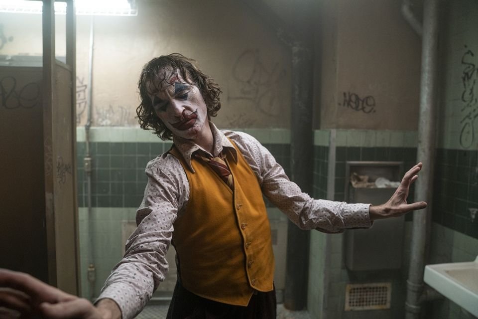 Como assistir aos filmes do Coringa na ordem? Veja lista! O Coringa, o mais famoso vilão do universo do Batman, é uma figura que sempre cativou e intriga o público. Com um histórico de interpretações memoráveis, suas aparições no cinema, tanto como protagonista quanto coadjuvante, se tornaram um marco no mundo dos filmes de super-heróis. A-fotografia-mostra-o-personagem-coringa-interpretado-por-joaquim-phoenix