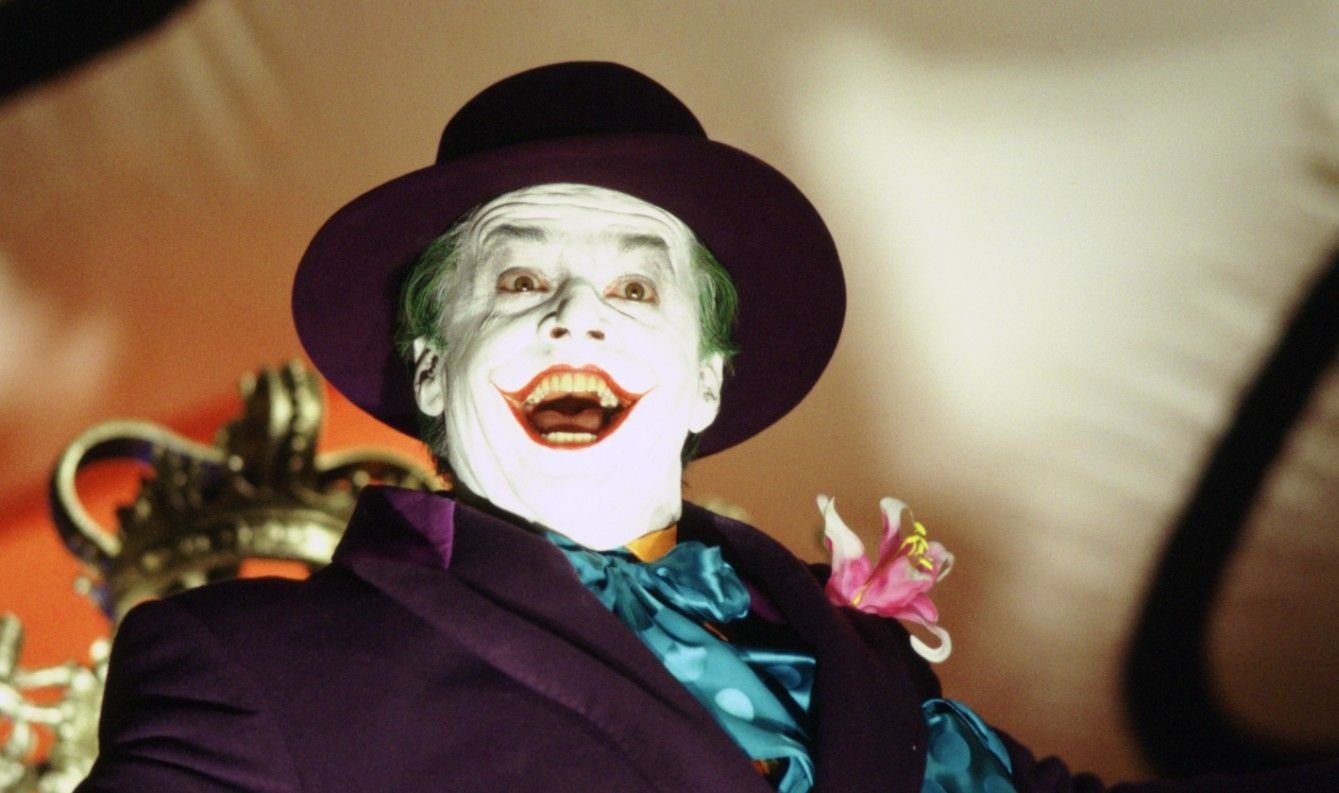 Como assistir aos filmes do Coringa na ordem? Veja lista! O Coringa, o mais famoso vilão do universo do Batman, é uma figura que sempre cativou e intriga o público. Com um histórico de interpretações memoráveis, suas aparições no cinema, tanto como protagonista quanto coadjuvante, se tornaram um marco no mundo dos filmes de super-heróis. a-captura-de-tela-mostra-uma-cena-do-fime-batman-mostrando-o-coringa-interpretado-por-jack-nicholson