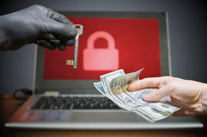 pessoa-segurando-chave-e-notas-de-dolar-em-frente-ao-notebook