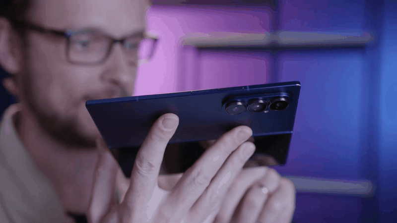 Homem caucasiano segura o Samsung Galaxy Fol 7, mostrando a parte traseira do celular, com foco nas câmeras.