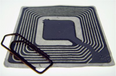 Uma etiqueta de RFID juntamente de um clipe para a comparação de tamanho